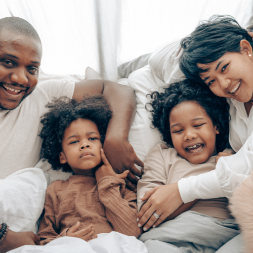 Family sitting on their sofa while cuddling their young kids